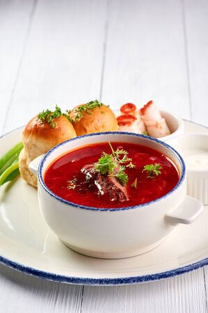 borsch with pampushkas, lard and onion at white table top. borsch is traditional ukrainian cuisine red soup with beet, potato, meat, carrot, cabbage and garlic. vertical shot with copy spaceの写真素材