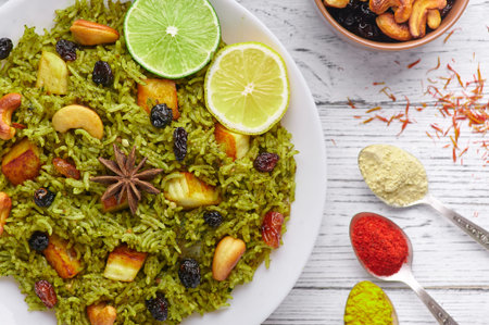 Palak Paneer Biryani and Raita at white wooden background with decor. Palak Paneer Biryani is...