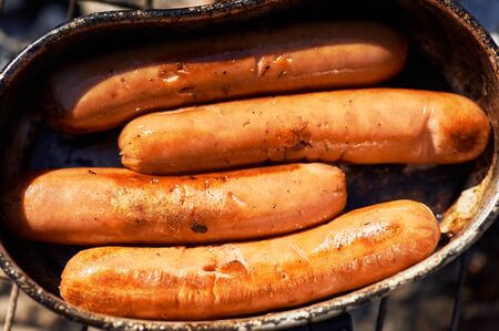 sausages fries at bonfire coals. cooking at campfire. Trekking or hiking cuisine. Close upの写真素材