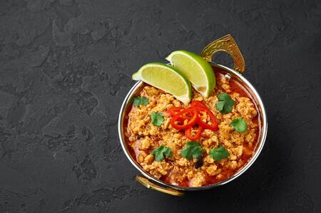 Chicken keema in traditional indian copper kadai at dark slate background. Kheema is indian and pakistani cuisine curry dish with minced meat and spices. Copy spaceの写真素材