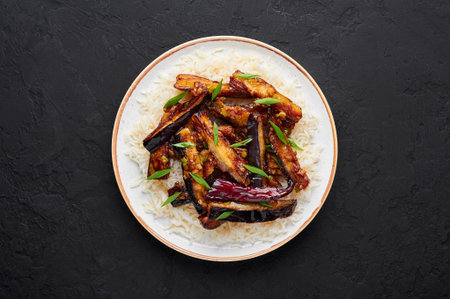 Sichuan Eggplant Stir Fry in black bowl at dark slate background. Eggplant Stir Fry is chinese...