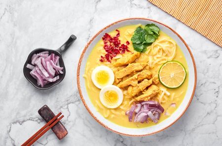 Ohn No Khao Swe on white marble background. Oh No Khao Suey is Coconut Milk Noodle Soup of myanmar cuisine with chicken meat and eggs. Burmese food. Top viewの写真素材