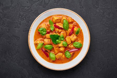 Thai Panang Chicken Curry in white plate at black slate background. Phanaeng Curry is thai cuisine dish with chicken, kaffir lime leaves, red curry sauce and vegetables. Thai food. Thailand mealの写真素材