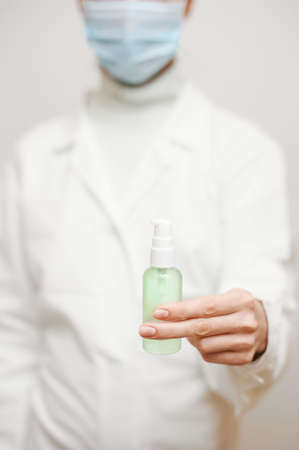 Close up view of female physician hands showing a personal antiseptic or sanitizer. Covid-19 protection measures. Doctor in white medical gown at clean white background.の写真素材