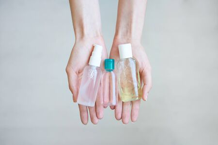 Three hands sanitizer in female hands. Woman keeps in palms several antiseptic bottles.の写真素材