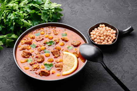 Moroccan Harira Soup in black bowl at dark slate bakcground. Harira is Moroccan Cuisine dish with...