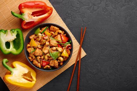 Gai Pad Med Mamuang or Thai Cashew Chicken in black bowl on dark slate backdrop. Kai Med Ma Muang is thai cuisine dish with chicken meat, capsicum, onion, scallions, chilli. Thai Food. Copy spaceの写真素材