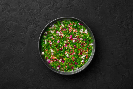 Pachi Pulusu in black bowl on dark slate table top. Raw Tamarind Rasam is indian cuisine soup dish....