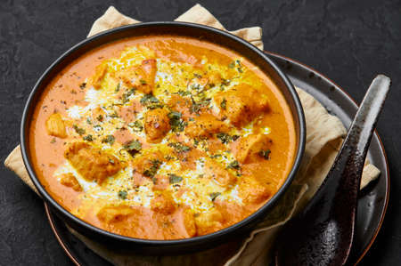 Murgh Makhani or Butter Chicken in black bowl on dark slate table top. Indian Cuisine dish with chicken meat and creamy masala. Asian food and meal. Close upの写真素材