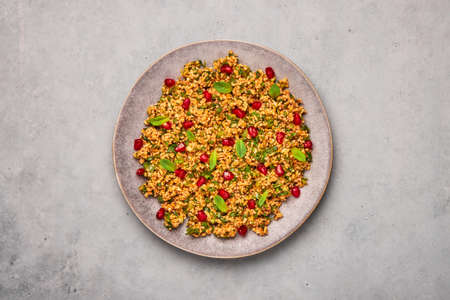 Kisir on gray plate on concrete table top. Turkish cuisine bulgur and parsley salad dish with pomegranate. Turkish food and meal.の写真素材