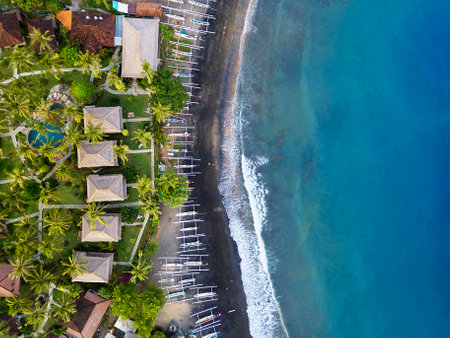 Aerial view of a tropical beach hotel with bungalows, palm trees on the ocean coast in Amed, Baliの写真素材