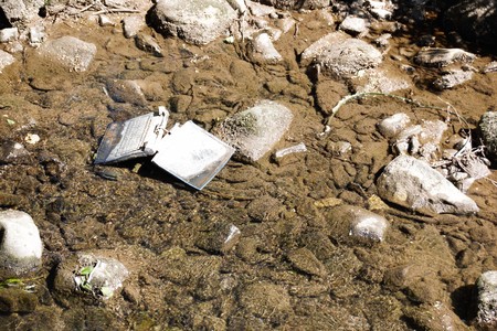 Laptop in the river / Carelessly discarded items pollute the environment and cause problems for all humanityの写真素材