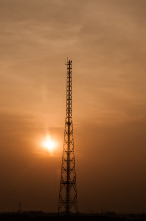 Silhouette of telecommunications tower on dramatic sunset skyの写真素材