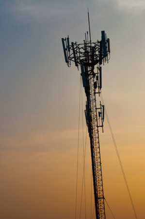 Silhouette of telecommunications tower on dramatic sunset skyの写真素材