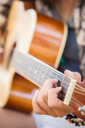 Closeup of young woman's hands playing acoustic guitar outdoorsの写真素材
