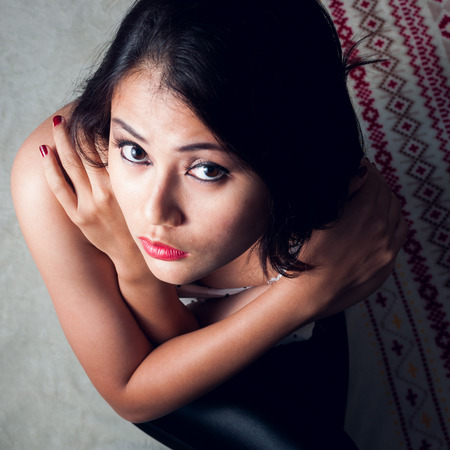 Glamorous young sexy woman sit on her bedの写真素材
