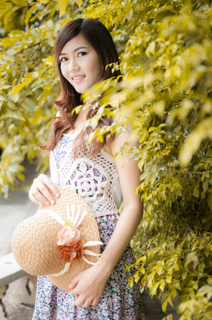 Smiling woman holding a hat in the parkの写真素材