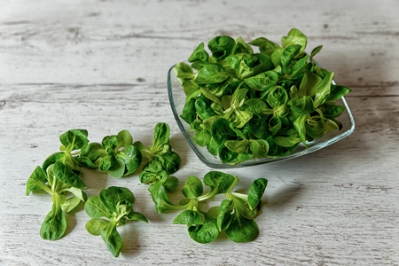 fresh lettuce leaves, salad on a plate placed on a wooden tableの写真素材