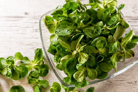 fresh lettuce leaves, salad on a plate placed on a wooden tableの写真素材