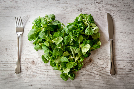 fresh lettuce leaves, salad on a plate placed on a wooden tableの写真素材