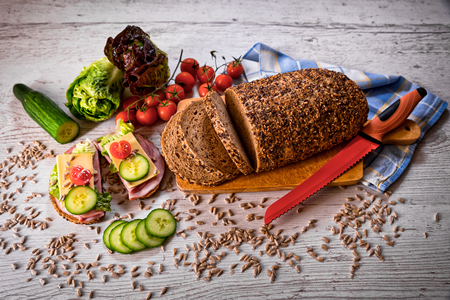 bread, fresh cereal bread with ham and vegetables, tasty healthy breakfast, top view, laid on the tableの写真素材