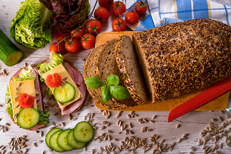 bread, fresh cereal bread with ham and vegetables, tasty healthy breakfast, top view, laid on the tableの写真素材