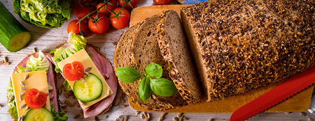 bread, fresh cereal bread with ham and vegetables, tasty healthy breakfast, top view, laid on the table, bannerの写真素材