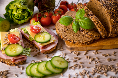 bread, fresh cereal bread with ham and vegetables, tasty healthy breakfast, top view, laid on the tableの写真素材