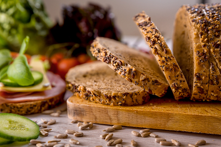 bread, fresh cereal bread with ham and vegetables, tasty healthy breakfast, top view, laid on the tableの写真素材