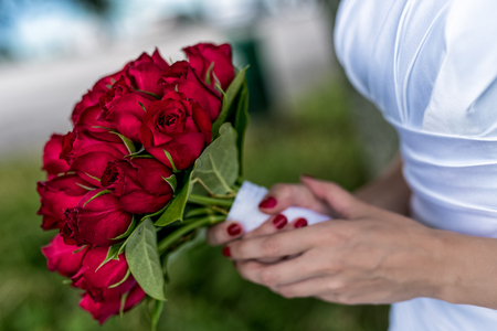 wedding bouquet, hands of bride holding a beautiful bouquet in hand, close-up of hands behind blurred backgroundの写真素材