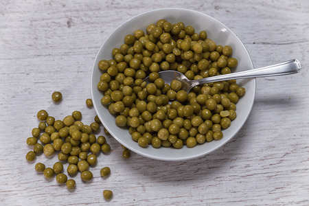 raw peas in a bowl and a wooden table healthy and freshの写真素材