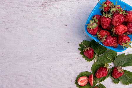 Fresh strawberries in mycell on a wooden table under a blue backgroundの写真素材
