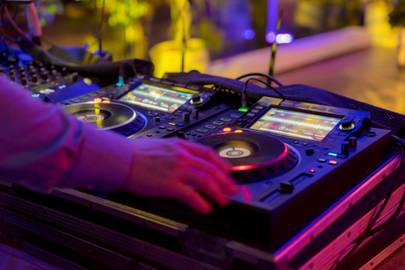 Professional sound mixer for musical events. hands of the DJ operator in the background colorful light atmosphereの写真素材