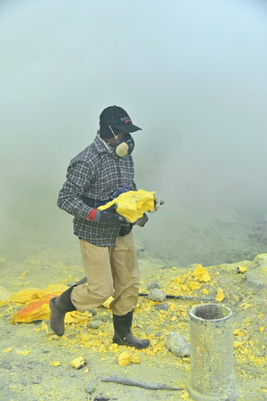 KAWAH IJEN, INDONESIA - OCT 18, 2015 : Worker carries sulfur sulphur inside Ijen crater in Ijen Volcano, Indonesia. Miners are extracting gaseous sulfur going out in the mine of the crater.のeditorial素材