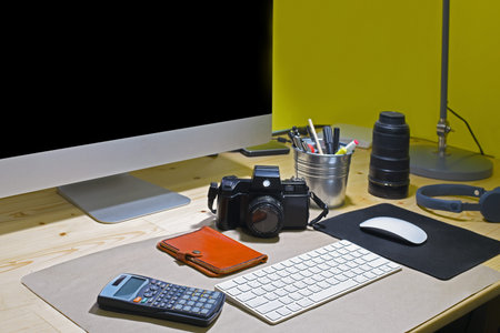 Close up of workplace with blank computer screen and accessories.
