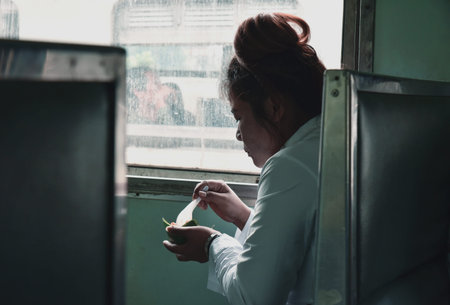 KANCHANABURI, THAILAND - MAR 29, 2015 : Woman traveling by the train eating near the window in...