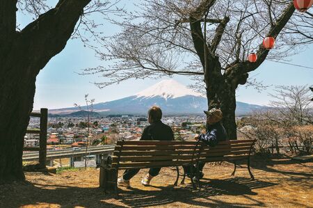 FUJIYOSHIDA - YAMANASHI, JAPAN - APRIL 07, 2014 : Tourists sitting on benches looking at Mt. Fuji from Chureito Pagoda.のeditorial素材