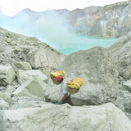 KAWAH IJEN, INDONESIA - OCT 18, 2015 : Worker inside Ijen crater in Kawah Ijen Volcano, Indonesia. Miners are extracting gaseous sulfur going out in the mine of the crater.のeditorial素材