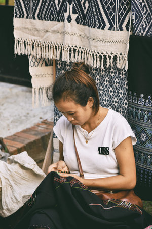 LUANG PRABANG, LAOS - MAY 4, 2015: Unidentified woman sewing clothes by hand at Luang Prabang...