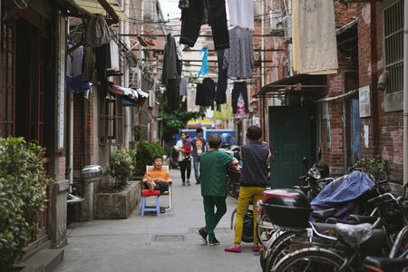 SHANGHAI, CHINA - MAY 18, 2019 : Unidentified people talking in front of their house with drying clothes outside on the clothes line in Hongkou District of Shanghai, China.のeditorial素材