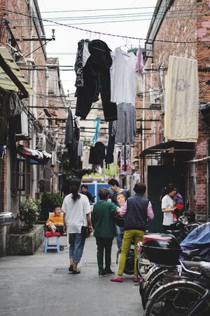 SHANGHAI, CHINA - MAY 18, 2019 : Unidentified people talking in front of their house with drying clothes outside on the clothes line in Hongkou District of Shanghai, China.のeditorial素材