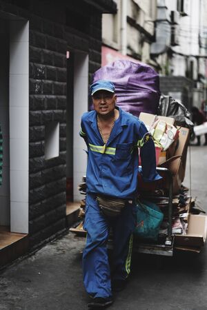 SHANGHAI, CHINA - MAY 18, 2019 : Unidentified man carrying boxes with a cart in Hongkou District of Shanghai, China.のeditorial素材