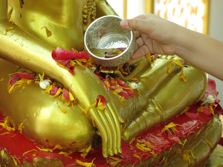 Water being poured over a Buddha statue as a part of Thais New Year celebrationの写真素材