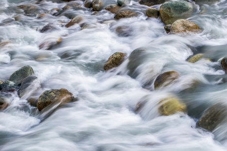 White silky water flowing downstream over the rocks and boulders