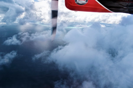 Aerial view from a seaplane flying through the clouds over Maldive island ocean sea for holiday...