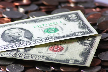 A set of two dollar bills on a pile of change.の写真素材