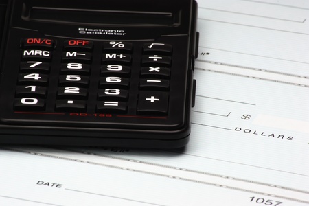 A black calculator on a sheet of blank checks.の写真素材