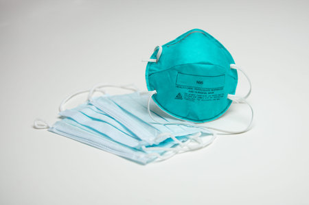 A closeup of an assortment of protective face masks. One N95 and three surgical masks.