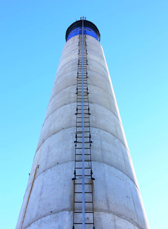 Shot of a blue, white and black chimney with a ladder, from the bottom up, against a blue sky.の写真素材