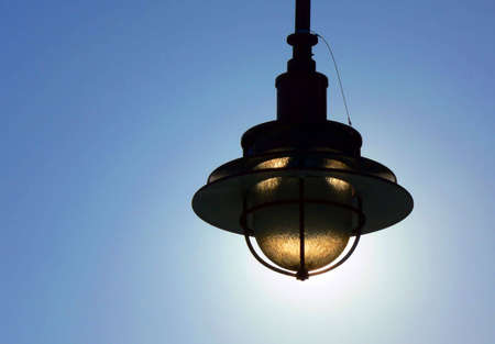 Exterior light fixture silhouetted against the sun.の写真素材